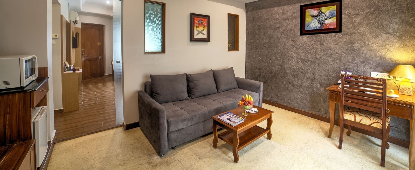 Spacious living room area with sofa, coffee table, and contemporary artwork at Ilara Hotels & Spa, OMR, Chennai