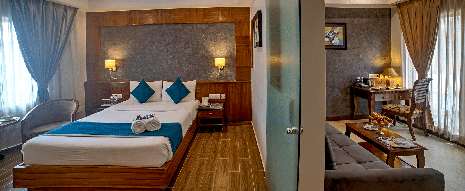 Elegant bedroom with a glass partition separating the living space at Ilara Hotels & Spa, OMR, Chennai