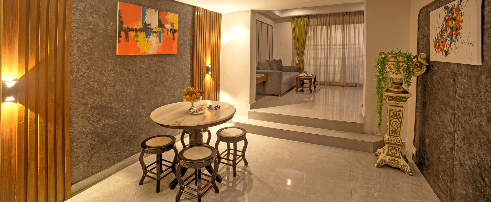 Cosy dining area with small round table, stools, and wall art in a softly lit corridor at Ilara Hotels & Spa, OMR, Chennai