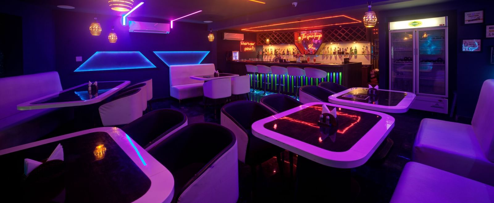 Lounge interior with glowing purple and blue lights and elegant white seating at Ilara Hotels & Spa, OMR, Chennai
