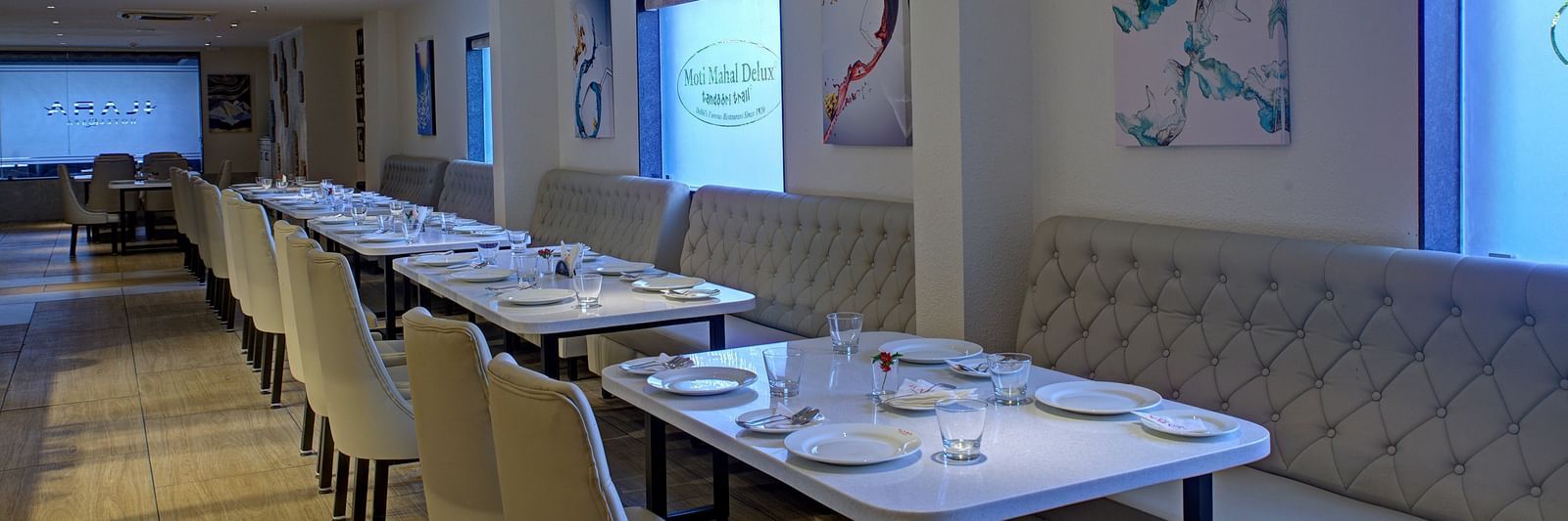 Corner view shot of the Moti Mahal Restaurant with dim lighting falling on the dining tables from the translucent glass windows at Ilara Hotels & Spa, Tada.