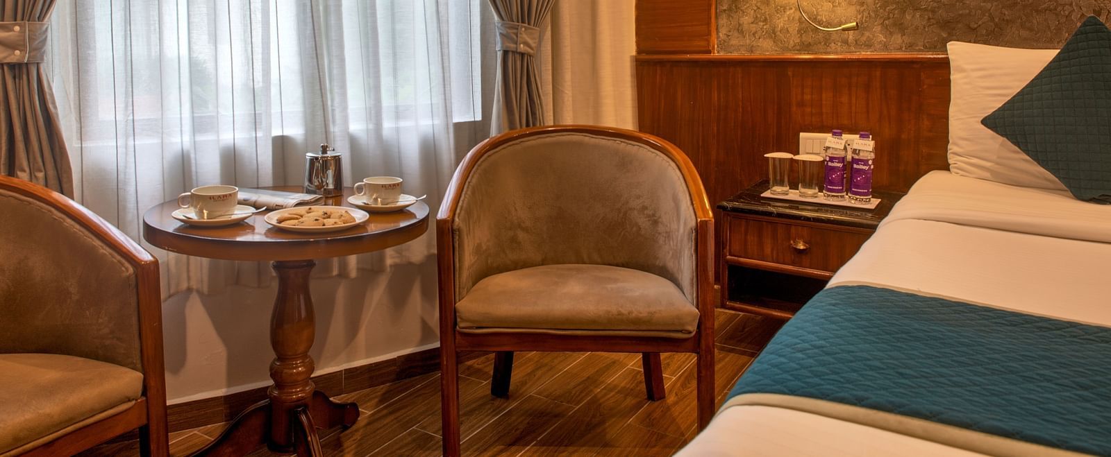 Cosy in-room seating with a round table and cushioned chairs by the window at Ilara Hotels & Spa, OMR, Chennai