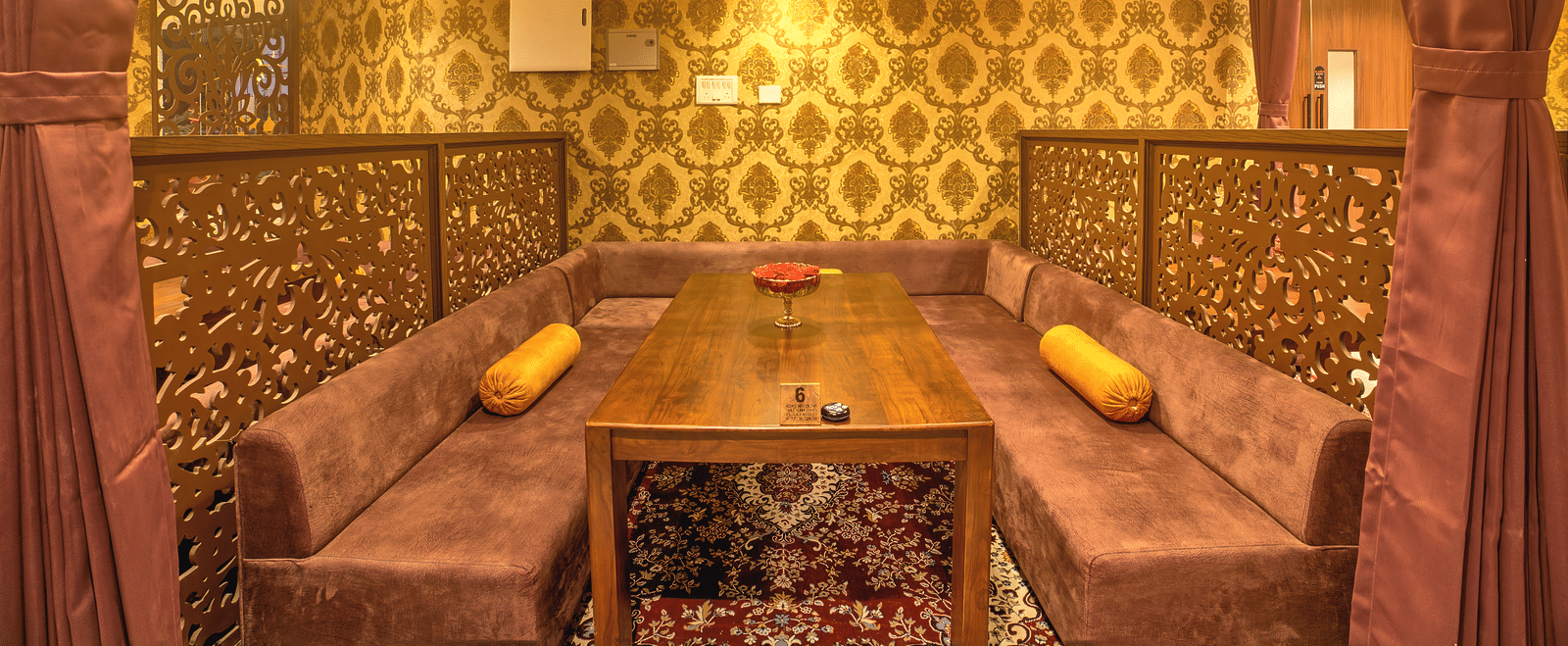 Stylish dining corner with ethnic gold patterns and soft lighting at Ilara Hotels & Spa, OMR, Chennai