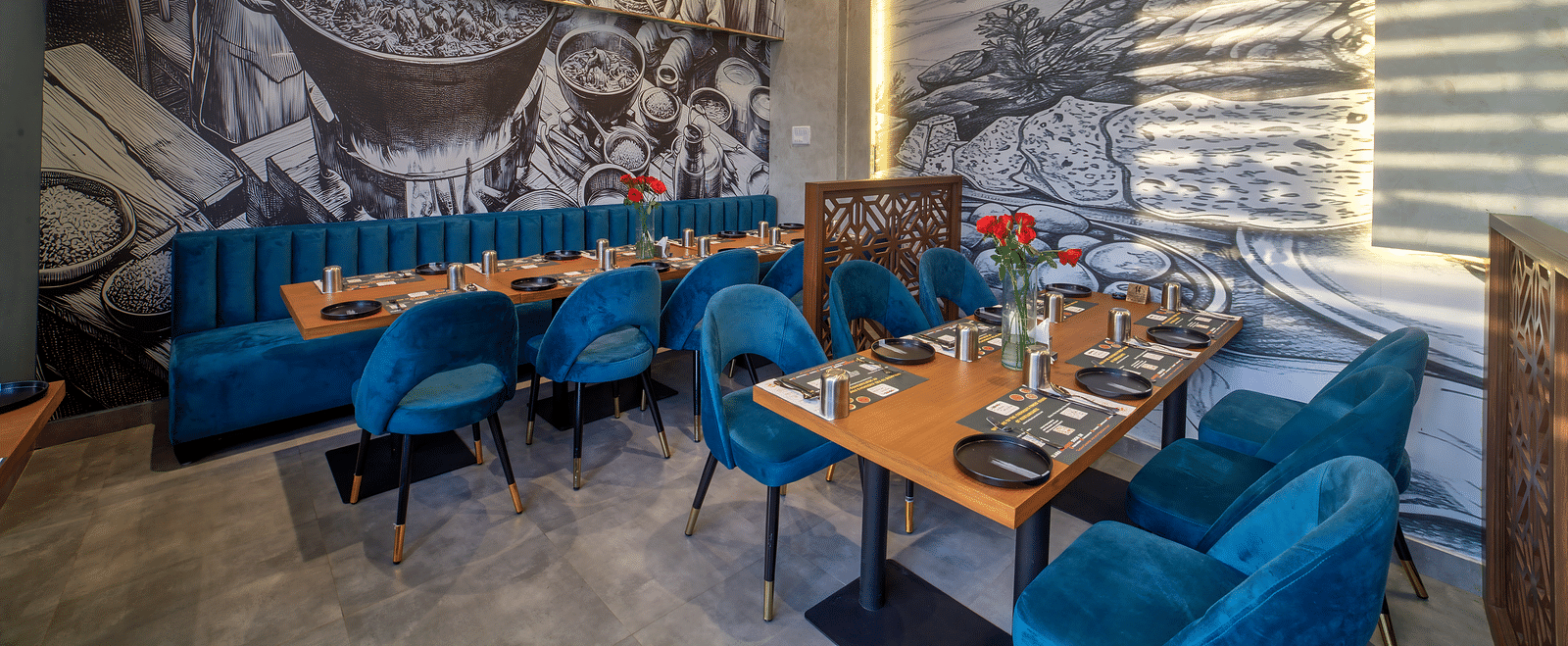 Cosy dining table setup with mural background and velvet chairs at Ilara Hotels & Spa, OMR, Chennai