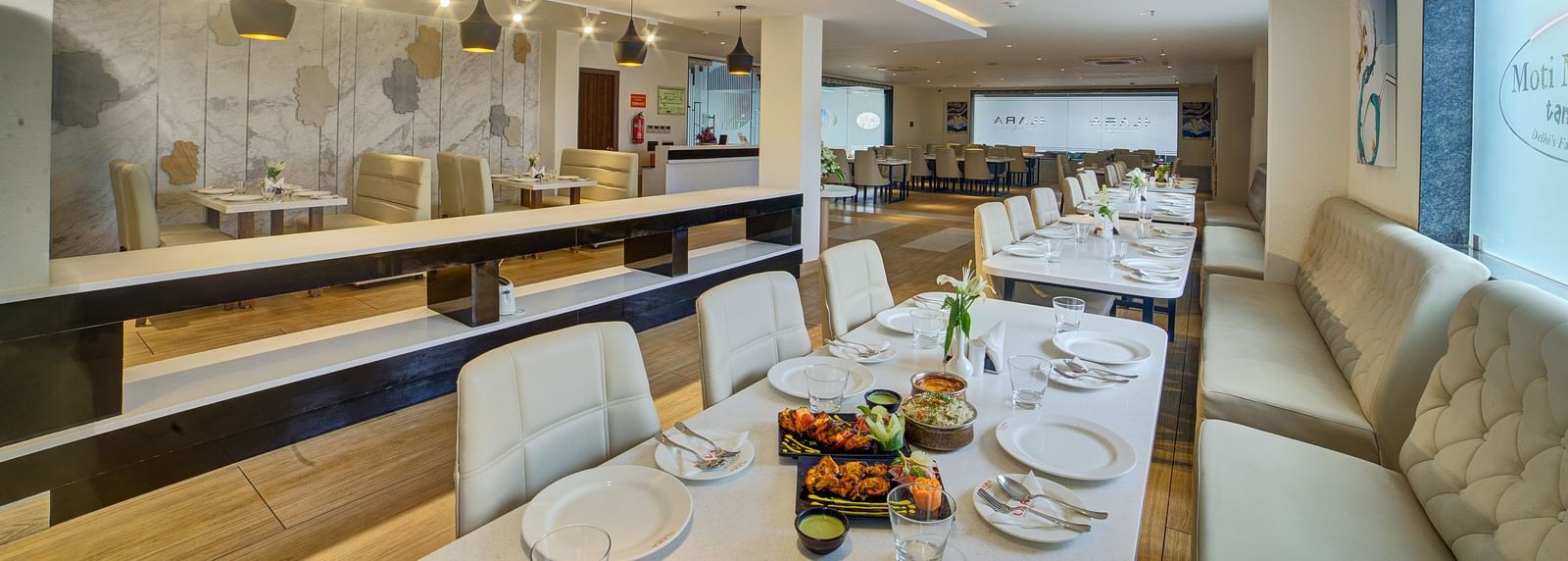 The interiors of a brightly lit dining area with beautifully served dishes on the table at Ilara Hotels & Spa, Tada.