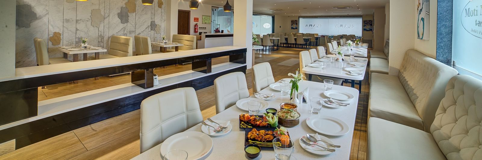The interiors of a brightly lit dining area with beautifully served dishes on the table at Ilara Hotels & Spa, Tada.