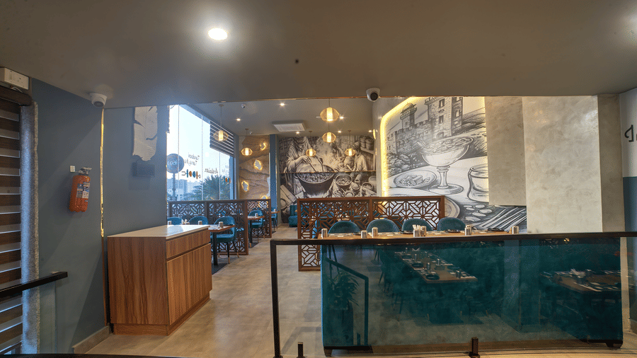 Artistic dining booths with blue seating and warm lighting at Ilara Hotels & Spa, OMR, Chennai