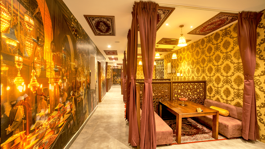 Themed restaurant with golden lighting, plush seating, and ornate décor elements at Ilara Hotels & Spa, OMR, Chennai