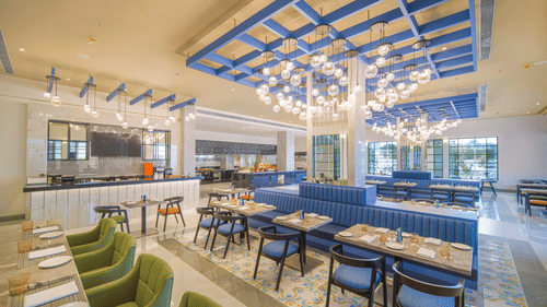 A spacious and stylish restaurant with blue and white patterned ceilings, multiple dining tables, and large windows | SPR Kitchen | Sarovar Portico, Sriperumbudur