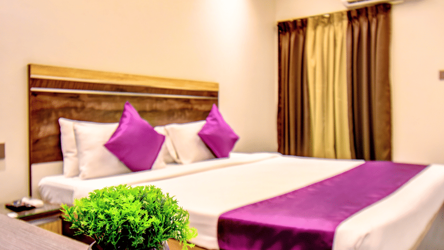 Super Deluxe Room king bed with purple pillows and wooden headboard at VITS Select Kharadi Pune