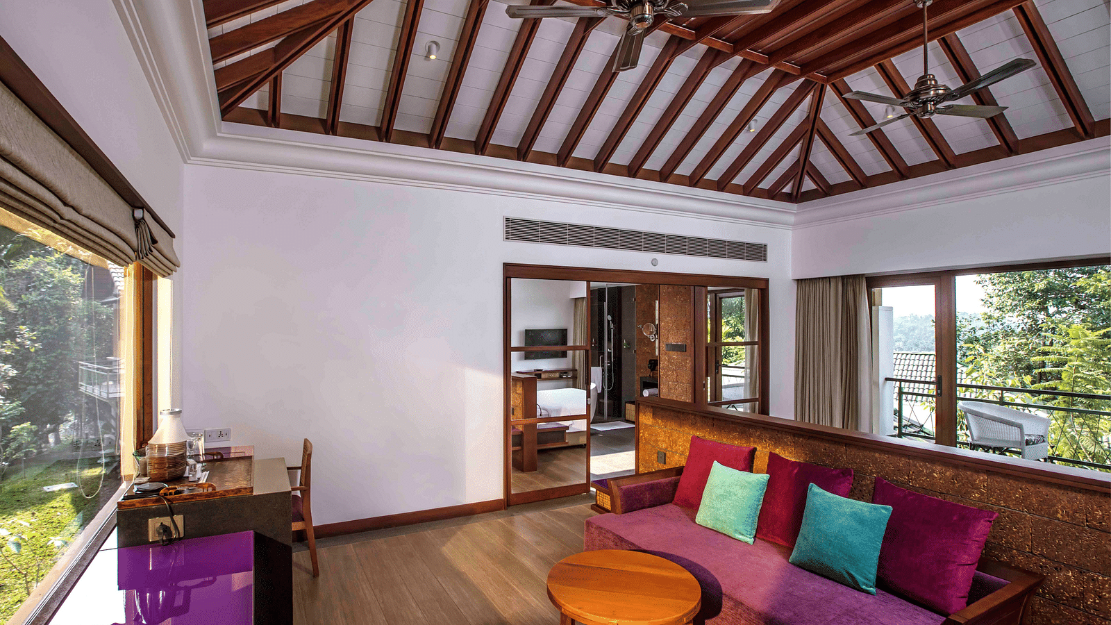 an image of a hotel room in Wayanad with a couch turned towards the beautiful view outside the room - GReaT trails Wayanad by GRT Hotels