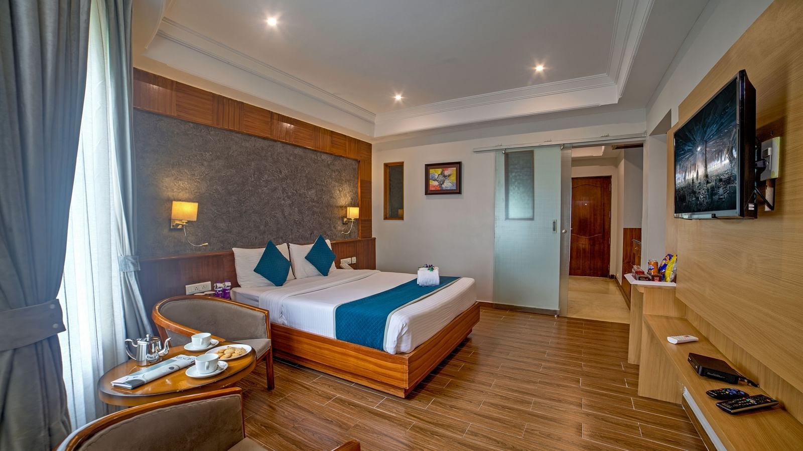Well-appointed guest room with wooden flooring, modern furnishings, and a cosy seating area at Ilara Hotels & Spa, OMR, Chennai