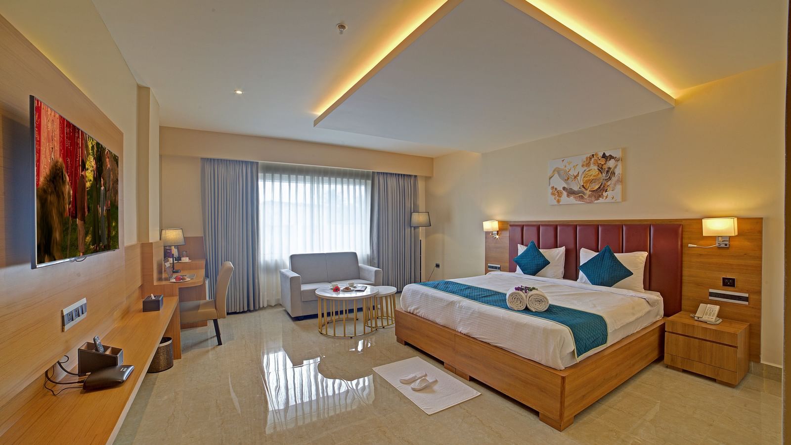 A brightly lit bedroom at the Junior Suite at Ilara Hotels & Spa, Tada with a double bed along with a bed side tables besides it.