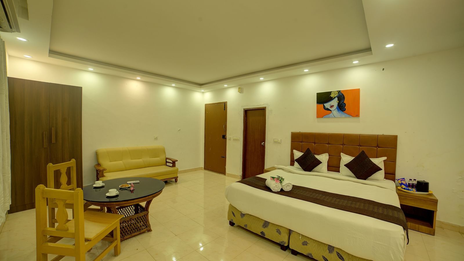 Spacious bedroom with soft lighting and a small dining setup at Kailash Conventions ECR.