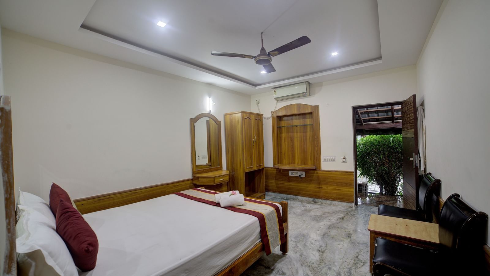 Well-furnished room with wooden decor and ceiling fan at Kailash Conventions ECR.