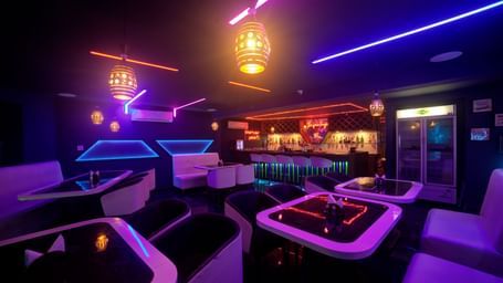 Lounge interior with glowing purple and blue lights and elegant white seating at Ilara Hotels & Spa, OMR, Chennai