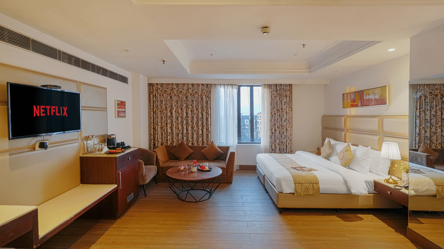 A hotel room featuring a bed and a separate seating area with a small, round coffee table and a velvet sofa at BluSalzz Select City Centre, Amritsar.