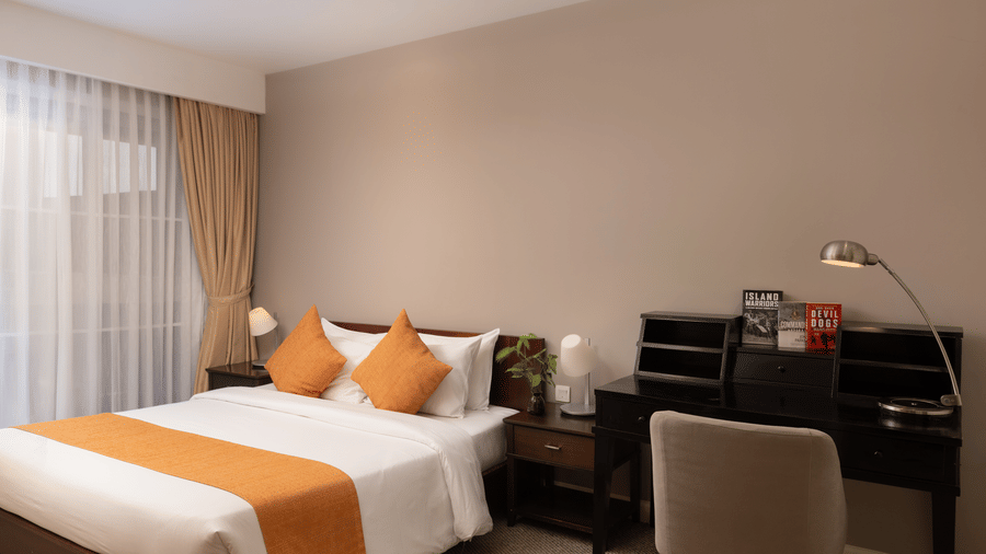 Penthouse bedroom at Central Mansions, Phnom Penh featuring a king bed, dedicated workspace, and floor to ceiling windows.