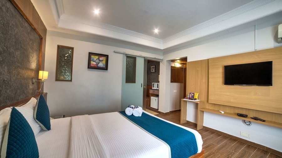 Modern bedroom with wooden flooring, soft lighting, and wall-mounted television at Ilara Hotels & Spa, OMR, Chennai