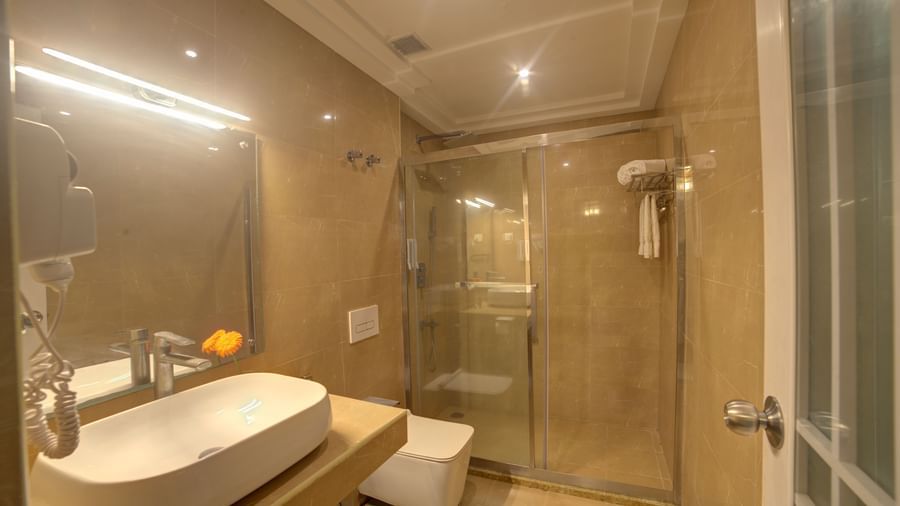 Modern bathroom with enclosed shower area and countertop sink at Ilara Hotels & Spa, OMR, Chennai