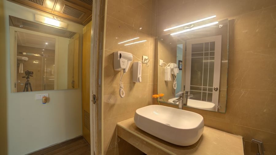 Elegant bathroom with twin mirrors, wash basin, and wall-mounted amenities at Ilara Hotels & Spa, OMR, Chennai