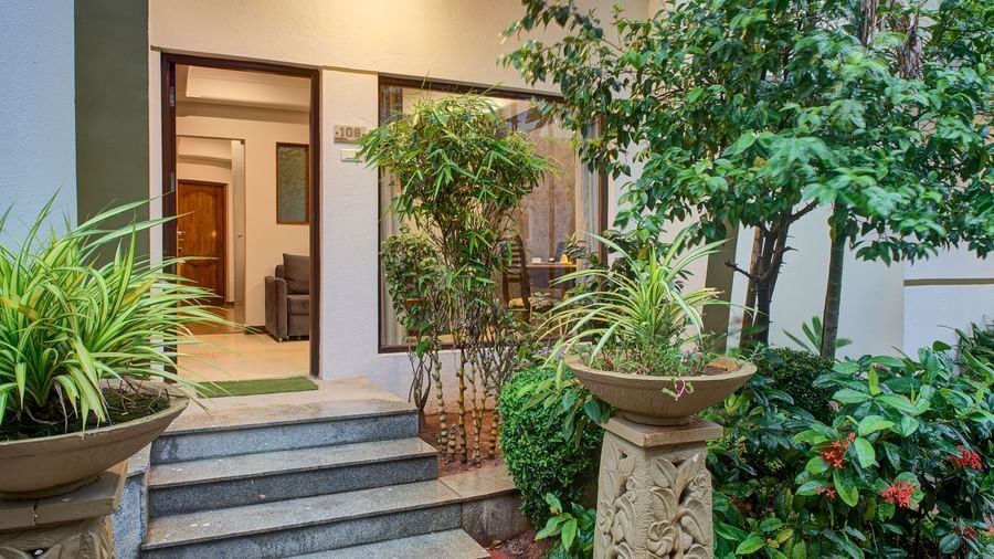 Charming entryway surrounded by lush green plants and stone decor at Ilara Hotels & Spa, OMR, Chennai
