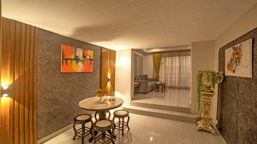 Cosy dining area with small round table, stools, and wall art in a softly lit corridor at Ilara Hotels & Spa, OMR, Chennai