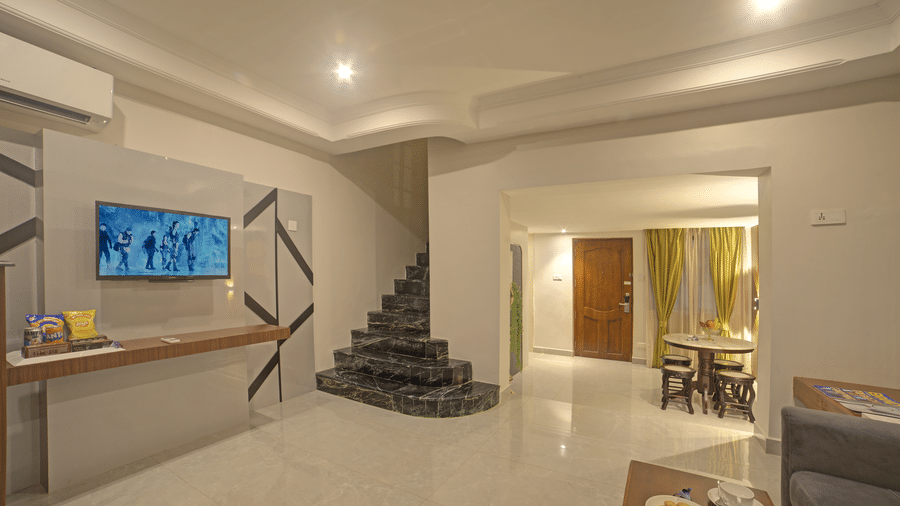 Spacious ground floor common area with spiral stairs, TV, and seating arrangement at Ilara Hotels & Spa, OMR, Chennai