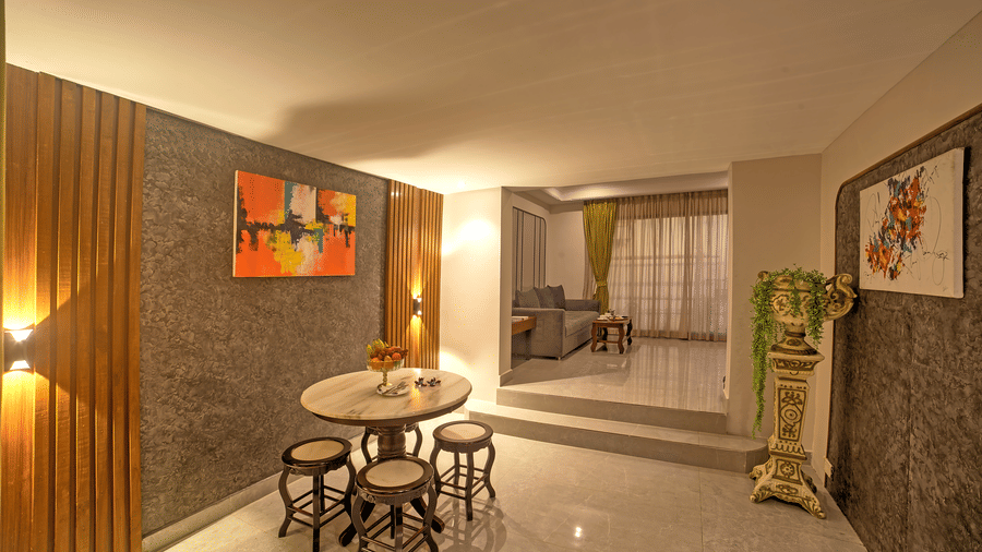 Cosy dining area with small round table, stools, and wall art in a softly lit corridor at Ilara Hotels & Spa, OMR, Chennai