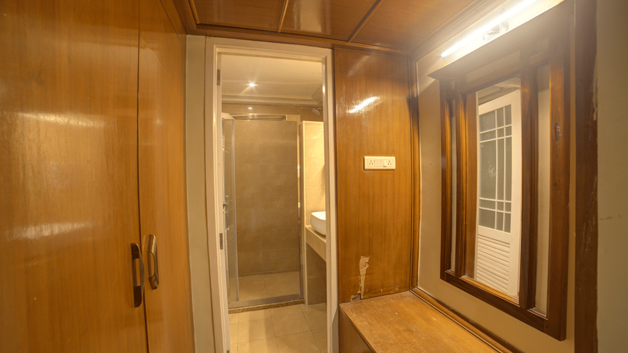 Changing area with wooden panelled wardrobe and enclosed glass door at Ilara Hotels & Spa, OMR, Chennai