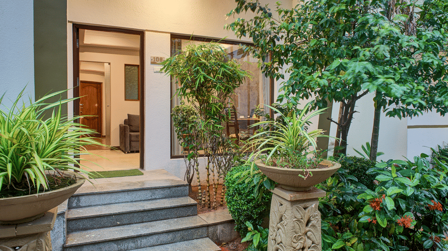 Charming entryway surrounded by lush green plants and stone decor at Ilara Hotels & Spa, OMR, Chennai