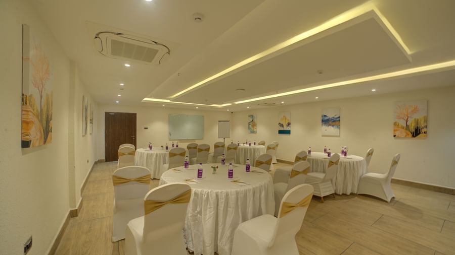 A spaciosu well lit banquet hall with a back lit false ceiling with chairs and tables arranged for an event at Ilara Hotels & Spa, Tada.