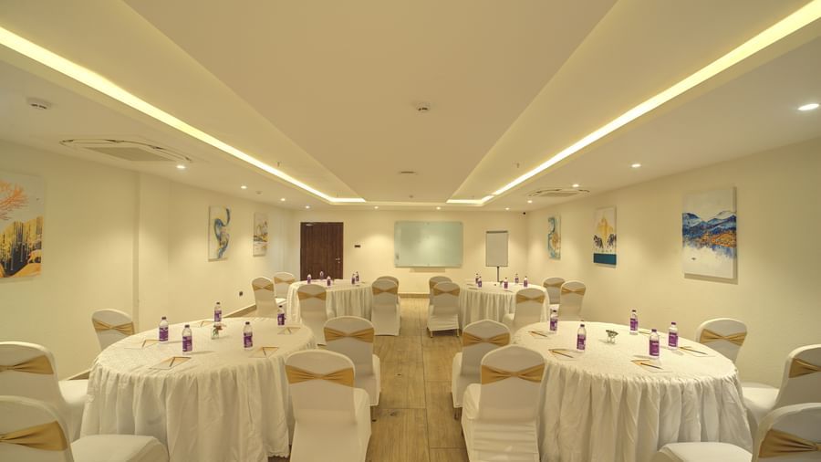 Full view shot of the banquet hall with some walking space in the middle leading towards the projector screen at the far end of the hall at Ilara Hotels & Spa, Tada.