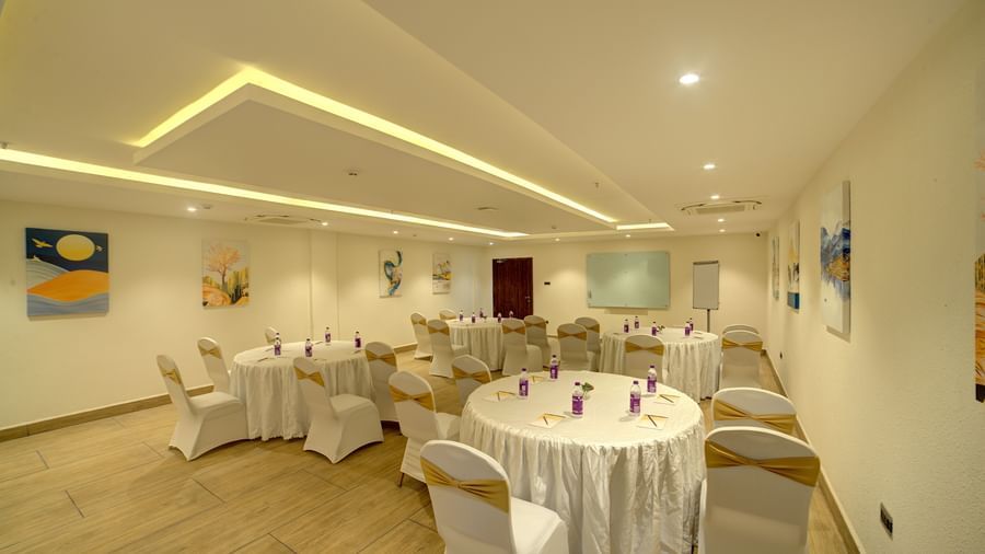 Corner view shot of a banquet hall with chairs and tables arranged for a fall event facing towards the projector at Ilara Hotels & Spa, Tada.