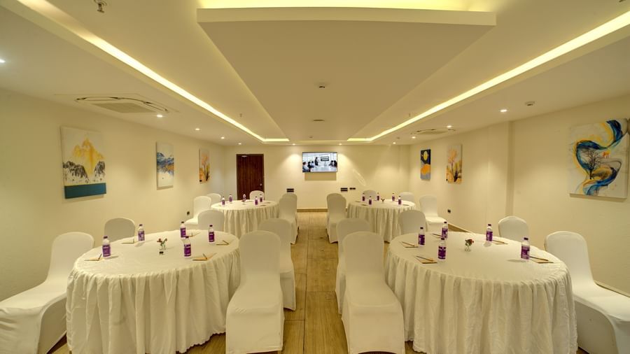 Front view shot of the banquet hall with several round tables with white table cloth surrounded by chairs at Ilara Hotels & Spa, Tada.