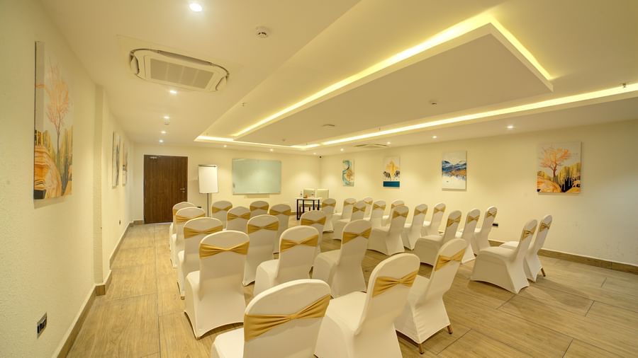 Full view shot of the banquet hall at Ilara Hotels & Spa, Tada with all the chairs arranged in a classroom setting facing towards the projector screen.