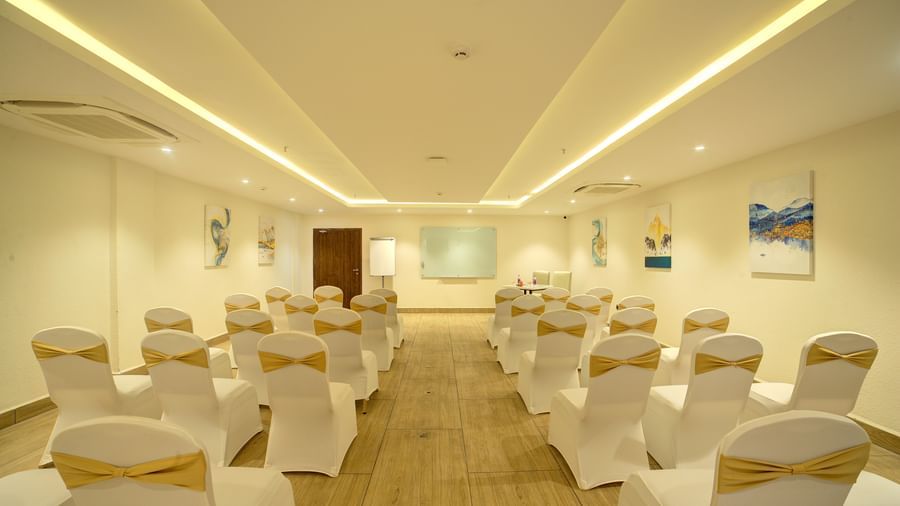 A wide passage in the middle of the banquet hall with chairs kept in three in a row on both sides at Ilara Hotels & Spa, Tada.