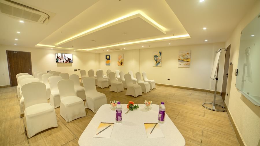Corner view shot of the banquet hall featuring a table in the foreground with some stationary and packed water bottles at Ilara Hotels & Spa, Tada.