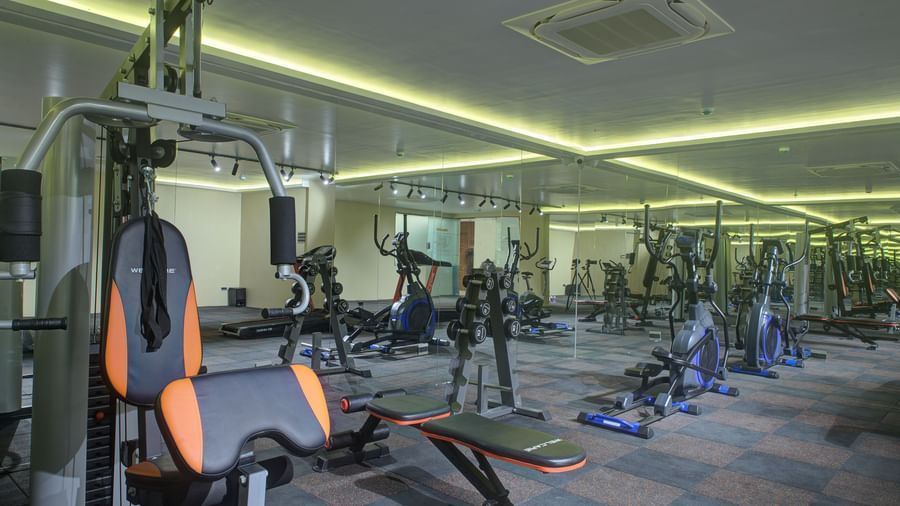A wide view of the fitness centre with various gym equipment and modern lighting at Ilara Hotels & Spa, Tada.