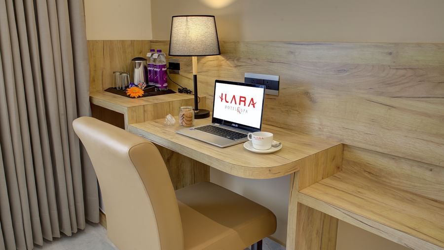 Close up shot of the work desk and chair with an open laptop kept on the desk alongside a coffee cup at the Junior Suite at Ilara Hotels & Spa, Tada.