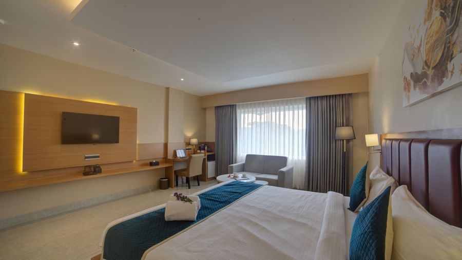 A wide angle shot of the Junior Suite with a double bed overlooking the wall mounted television at Ilara Hotels & Spa, Tada.