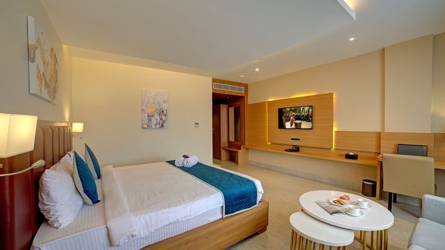 Corner view shot of the Junior Suite featuring a coffee table kept besides the double bed at Ilara Hotels & Spa, Tada.