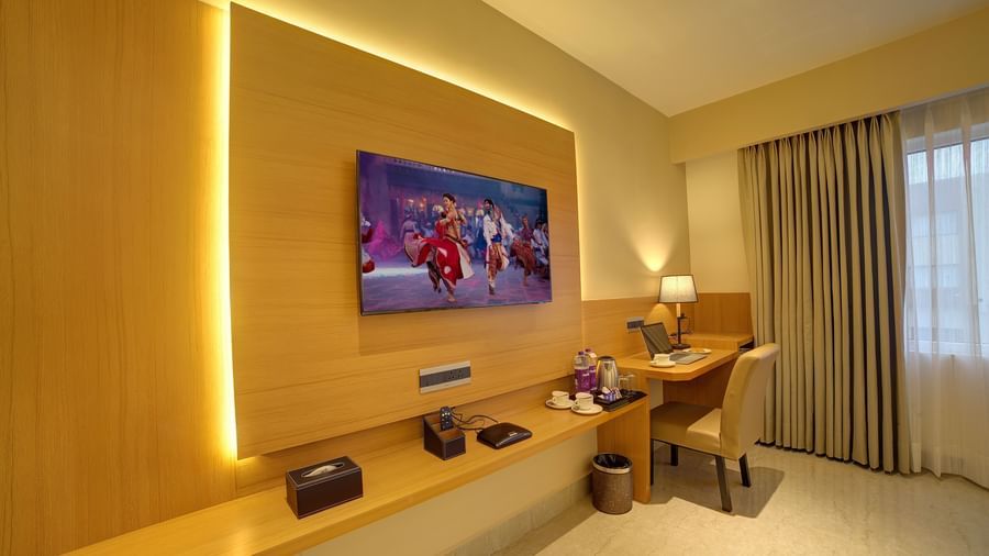 Corner view shot of the TV table with a wall mounted flat screen television and a work station in the corner of the Signature Suite at Ilara Hotels & Spa, Tada.