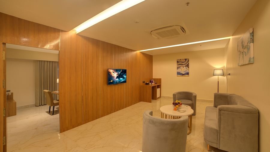A separate living room featuring a grey coloured couch set with a wall mounted television on wooden panels at the Executive Suite of Ilara Hotels & Spa, Tada.