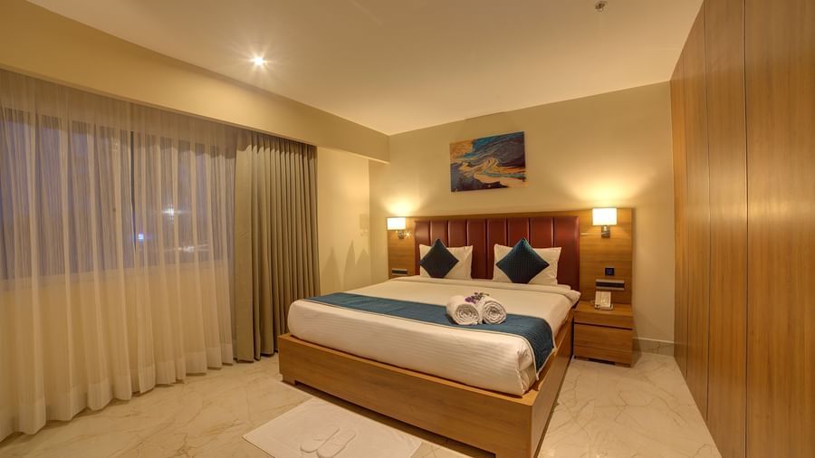A close up shot of a plush double bed with two bed side lamps in the Executive Suite and a white rug in front of it at Ilara Hotels & Spa, Tada.