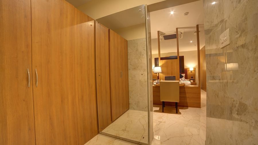 A full length mirror besides the wooden wardrobe at the Executive Suite with a doorway going leading to the bedroom at Ilara Hotels & Spa, Tada.
