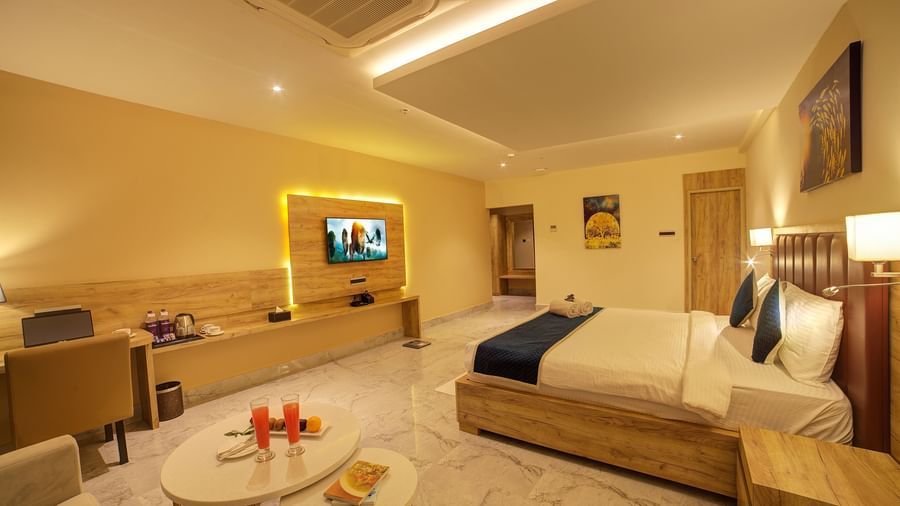 A wide angle shot of the Junior Suite with a coffee table along with a double bed and a wall mounted television and a work station.