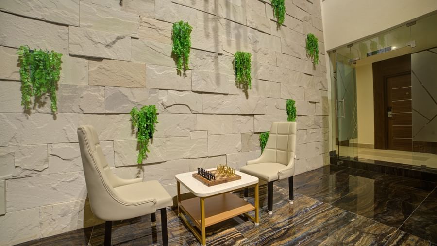 Two white chairs placed opposite to each other with a small table along with a chess board on it at Ilara Hotels & Spa, Tada.