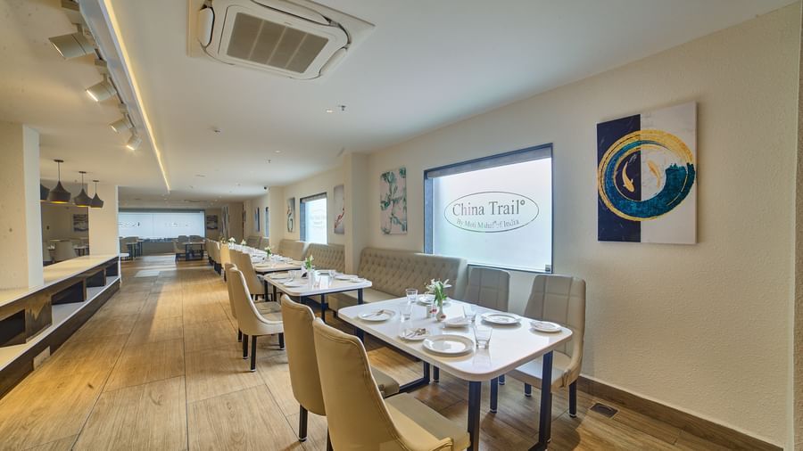 Side view of the seating area at the Moti Mahal restaurant with a wide translucent glass partition behind the tables at Ilara Hotels & Spa, Tada.