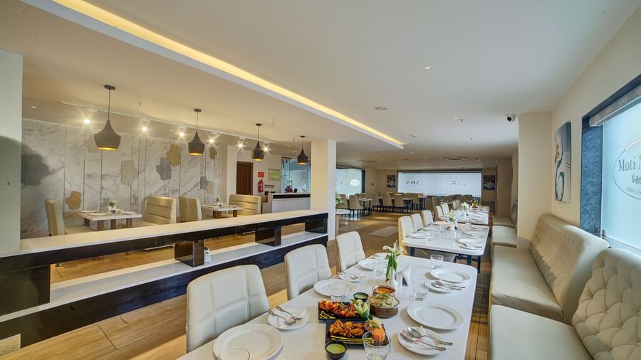 The interiors of a brightly lit dining area with beautifully served dishes on the table at Ilara Hotels & Spa, Tada.